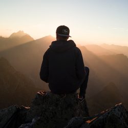 man sitting on the mountain edge